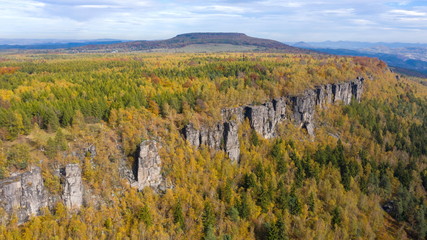 Natural rock wall in autumn colored forrest, Tisa Rocks, Czechia. Aerial shot.