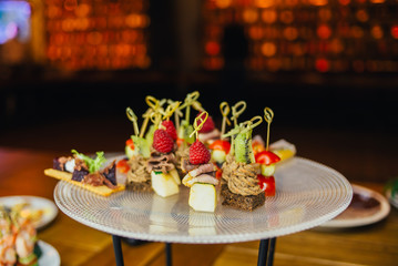 the buffet at the reception. Glasses of wine and champagne. Assortment of canapes on wooden board. Banquet service. catering food, snacks with cheese, jamon, prosciutto and fruit