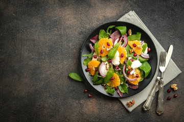 Detox salad with tangerines, mozzarella, herbs, pomegranate seeds and nuts on a dark background....