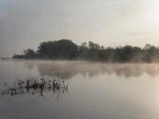 Obraz na płótnie Canvas Mist over the water in the morning sun. Landscape.