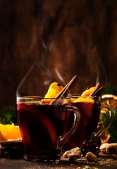 Xmas hot mulled red wine with spices and fruits on wooden rustic table. Traditional Christmas hot...