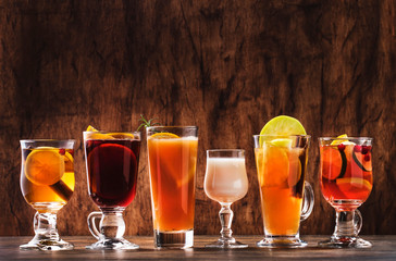 Selection of autumn or winter seasonal alcoholic hot cocktails - mulled wine, glogg, grog, eggnog, warm ginger ale, hot buttered rum, punch, mulled apple cider on wood background, copy s