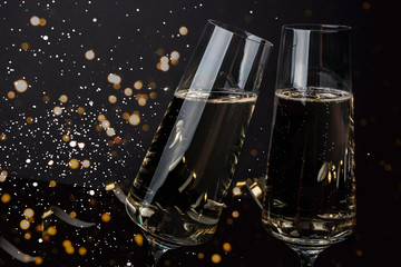 Champagne glasses on a dark background with snow and lights. New year's eve, Christmas