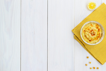 Hummus with chickpeas, paprika and butter in a bowl on a wooden table. Horizontal orientation, copy space.