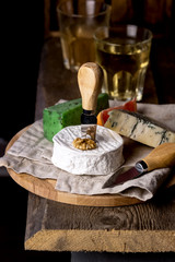 Tasty Cheese Variety of Cheese with Nuts on Linen Napkin Wooden Tray Wooden Background Vertical Cheese Knives Vertical Two Glasses of White Wine
