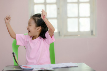 An Asian kindergarten girl is coloring on the table.