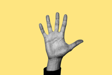 Concept of helping, life difficulties, having a problem. Hand at the center of the image in a sign of requesting help. Hand in black and white. Yellow background