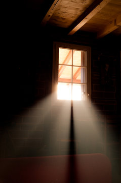 Basement windows in wooden cabin house. Light beams passing through them