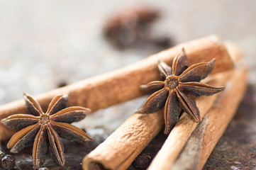 Cinnamon sticks, anise stars and black peppercorns on textured background