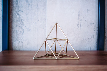 Wire shape metal pyramid on the office shelves. Interior decoration