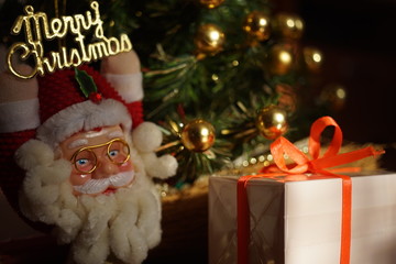 Gift box with orange ribbon and santa claus on christmas tree background.