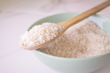  rice wooden spoon on white marble background. close-up, sprinkled rice