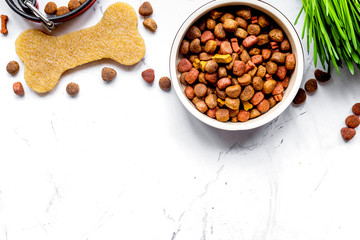 dry dog food in bowl on stone background top view