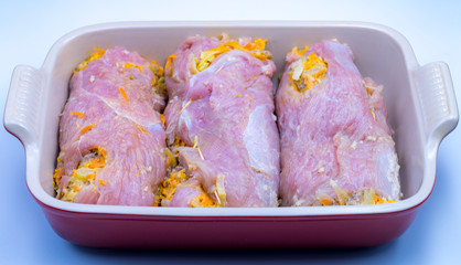 In a special baking dish, there are three turkey rolls with vegetables. The rolls are not yet baked.