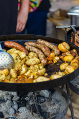 chef cooks potatoes and sausages at the street food festival