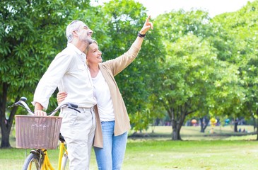 couple senior happily strolling in the park with bicycles. The concept of living a happy life in...