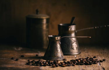 Old coffee pot and coffee bean on rustic wooden table. Vintage oriental coffee on dark background.