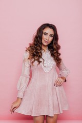 Portrait of a beautiful fashionable woman with haircurls in a pink holiday dress