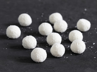 Dessert curd balls in coconut shavings on a dark gray background