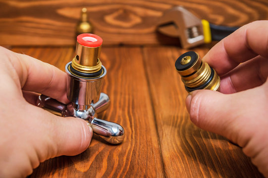 Cruciform hot and cold water main switch of spare parts holding in his hands master plumber