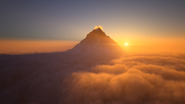 Mountain peak above the clouds at sunset