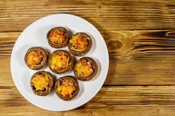 Baked mushrooms stuffed with minced meat, mushroom, paprika, onion and cheese on wooden table. Top view