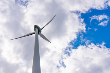 Single Wind Turbine under blue sky with clouds. Windfarm, wind power plant