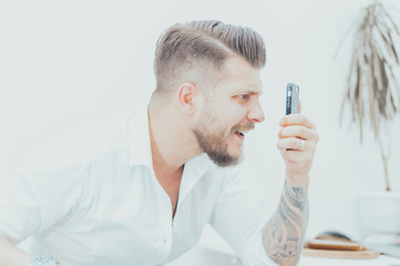 Man in a shirt looks at the smartphone screen in surprise. Concept of unsuccessful betting on...