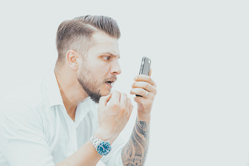 Man in a shirt looks at the smartphone screen in surprise. Concept of unsuccessful betting on...