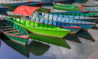 Blue and green wooden boats in the Phewa Lake of Pokhara, Nepal