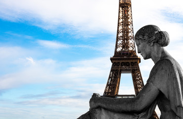 Fototapeta na wymiar The Eiffel Tower in Paris in the arms of a statue of a seated woman