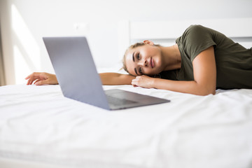 Portrait of a relaxed young woman using laptop in bed at home