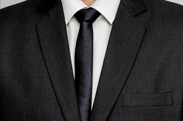 man in tie and suit close-up. the texture of a business black jacket. business style in clothes background