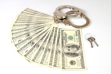 Close-up of metal handcuffs, keys and american dollars cash pack