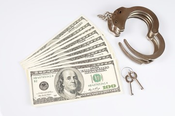 Open metal handcuffs, keys and stack of american dollars cash