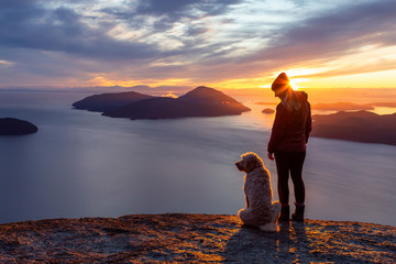 Adventurous Girl Hiking on top of a Mountain with a dog during a colorful sunset. Taken on Tunnel...