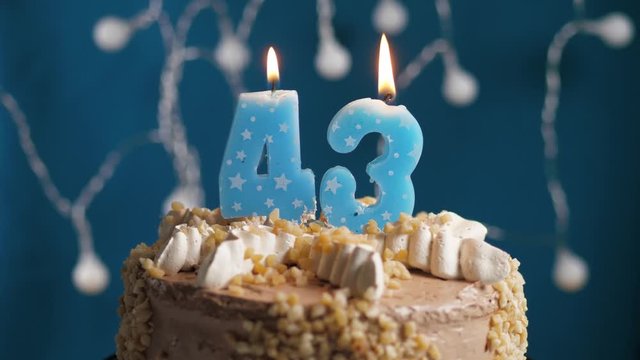 Birthday cake with 43 number candle on blue backgraund. Candles blow out. Slow motion and close-up view