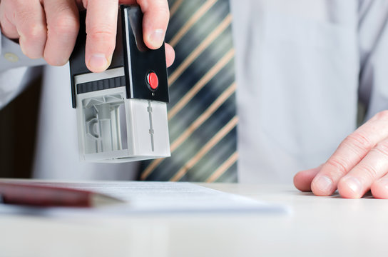 A Lawyer Or Notary Puts A Seal On The Document. A Stamp In A Man's Hand.