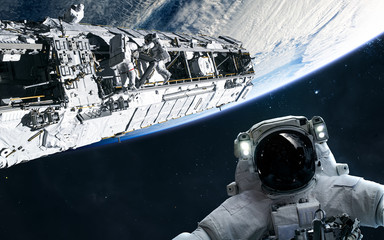 Astronaut and space station in orbit of the Earth. Solar system. Science fiction. Elements of this image furnished by NASA