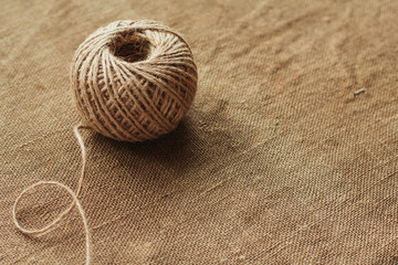 Reel of jute twine on a background of old burlap copy space. Needlework rope.
