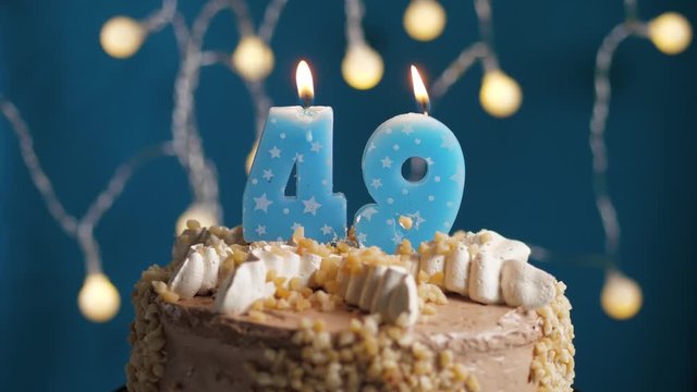 Birthday cake with 49 number candle on blue backgraund. Candles blow out. Slow motion and close-up view