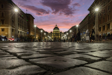 Fototapeta na wymiar Cobbestone street lit up at dusk with view of Saint Peter's Square in the Vatican