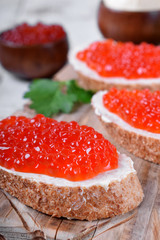Sandwiches with bran bread, red caviar and butter on white wooden table