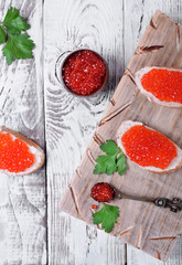 Sandwiches with bran bread, red caviar and butter on white wooden table