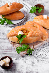 Rasstegai pie of yeast dough with meat filling on white wooden table. Traditional meal of Russian cuisine