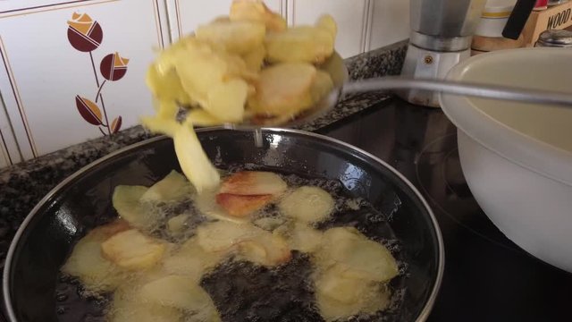 Potatoes frying in olive oil in a pan. Spanish tortilla elaboration process. Spanish and homemade cuisine.