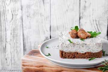 Salty mini cheesecake with roasted mushrooms and parsley on a ceramic plate