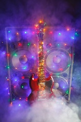 abstract guitar with festive Christmas lights and music speakers in smoke