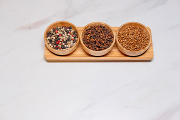 set of spices colored pepper cloves coriander in wooden cups on the table