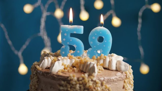 Birthday cake with 59 number candle on blue backgraund. Candles blow out. Slow motion and close-up view